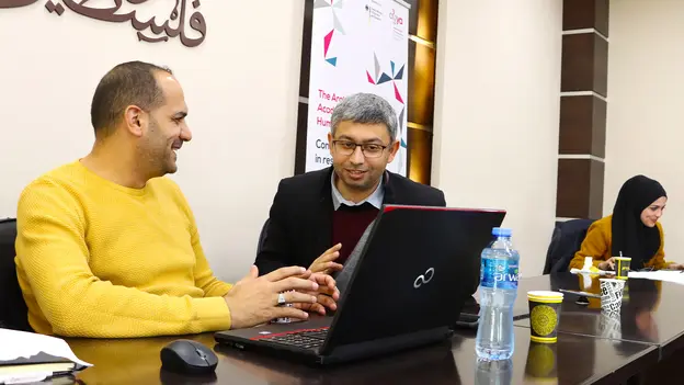 AGYA Member Mohammad Adm in discussion with a participant in front of a computer