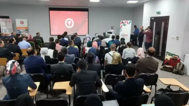 An audience of students and professionals attend a presentation.