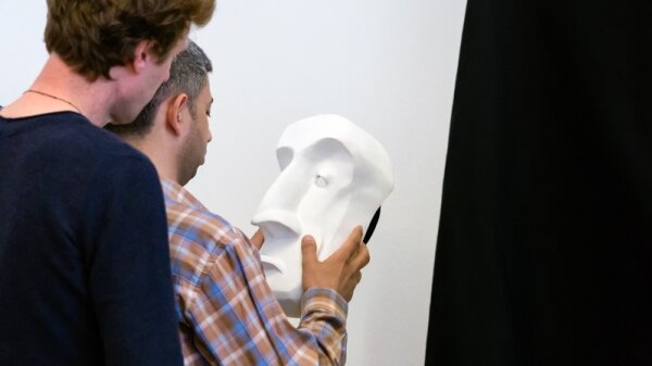 Two men looking at a sculpture of a face